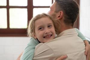 une peu fille exprime le sien sentiments pour le sien père. par embrassement comme bientôt comme vous réveiller en haut dans le début de le journée photo