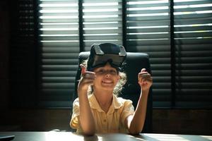 portrait de peu fille dans Bureau pièce de maison avec gestes cette sont exprimé lorsque en jouant virtuel réalité Jeux photo