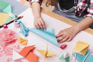 Artiste féminine pliant du papier origami faisant de beaux métiers photo