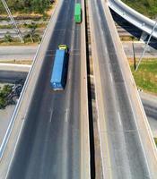 aérien vue de cargaison un camion sur Autoroute route avec bleu et vert récipient, transport concept., importation, exportation la logistique industriel transportant terre transport sur le asphalte voie express photo