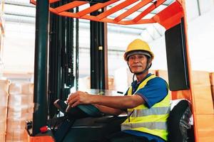 ouvrier chauffeur asiatique homme dans protecteur sécurité combinaison uniforme avec Jaune casque à entrepôt chariot élévateur chargeur travaux photo