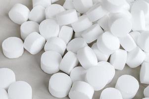 blanc rond grand pilules sont épars sur le tableau. sel capsules isolé Haut vue photo