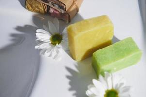 Fait main biologique éco savon avec Naturel Ingrédients de olive pétrole et camomille sur blanc céramique lavabo photo