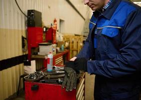 fermer de une voiture ingénieur, mécanicien, technicien en mettant sur protecteur travail gants avant essai une voiture dans réparation magasin. voiture réparation et entretien concept photo