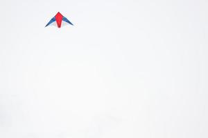 coloré cerf-volant en forme de comme des oiseaux est soufflant sur blanc ciel photo