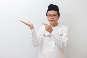 portrait de Jeune asiatique musulman homme montrant produit et montrer du doigt avec le sien main et doigt. isolé image sur blanc Contexte photo