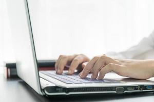 mains de femme tapant sur un clavier d'ordinateur portable photo