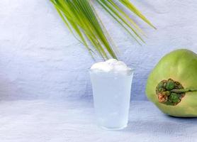 Boisson à l'eau de coco glacée dans un verre en plastique et noix de coco sur fond blanc photo