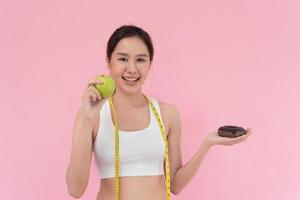 svelte corps femmes choisir pendant vert Pomme et Chocolat Donut, femelle choisir vert Pomme pour régime. bien en bonne santé aliments. poids perdre, équilibre, contrôle, réduire graisse, faible calories, routines, exercer. photo