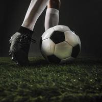 Jambes de récolte coups de pied dans un ballon de football sur l'herbe