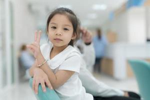 fille séance souriant dans le hôpital lobby. photo