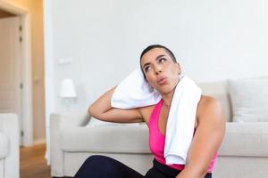 aptitude modèle. portrait de jolie souriant sportif noir femme dans tenue de sport ayant Pause après exercice avec serviette sur sa épaules, à la recherche loin, gratuit copie espace photo