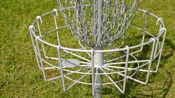 disque le golf panier. frisbee le golf est sport et Hobbie dans Extérieur parc. métal panier avec Chaînes pour disque Jeu entouré par vibrant vert des arbres. photo