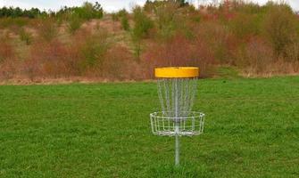 disque le golf panier. frisbee le golf est sport et Hobbie dans Extérieur parc. métal panier avec Chaînes pour disque Jeu entouré par vibrant vert des arbres. photo
