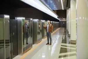 Un homme dans un masque facial utilise un smartphone en attendant une rame de métro photo