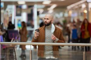 Un homme tient un masque décollé tout en buvant du café dans le centre commercial photo