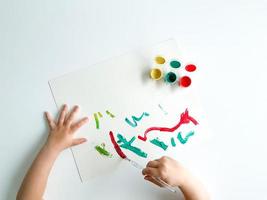 petit enfant dessine avec des peintures et brosse sur blanc tableau. les pères journée photo