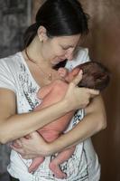 une Jeune mère détient une nouveau née bébé dans sa bras. photo