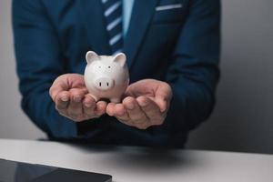 proche en haut vue de Jeune homme d'affaire en portant porcin banque dans le Bureau chambre. argent investissement concept. photo