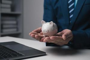 proche en haut vue de Jeune homme d'affaire en portant porcin banque dans le Bureau chambre. argent investissement concept. photo