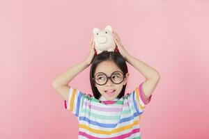 petite fille asiatique économisant de l'argent dans une tirelire, apprenant à économiser, enfant économisant de l'argent pour l'éducation future. concept d'argent, de finances, d'assurance et de personnes photo