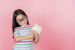 petite fille asiatique économisant de l'argent dans une tirelire, apprenant à économiser, enfant économisant de l'argent pour l'éducation future. concept d'argent, de finances, d'assurance et de personnes photo