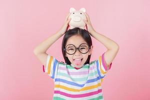 petite fille asiatique économisant de l'argent dans une tirelire, apprenant à économiser, enfant économisant de l'argent pour l'éducation future. concept d'argent, de finances, d'assurance et de personnes photo