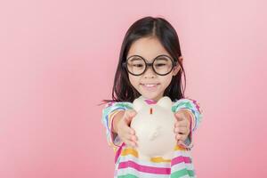 petite fille asiatique économisant de l'argent dans une tirelire, apprenant à économiser, enfant économisant de l'argent pour l'éducation future. concept d'argent, de finances, d'assurance et de personnes photo