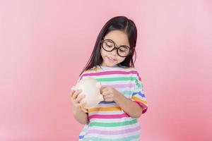 petite fille asiatique économisant de l'argent dans une tirelire, apprenant à économiser, enfant économisant de l'argent pour l'éducation future. concept d'argent, de finances, d'assurance et de personnes photo