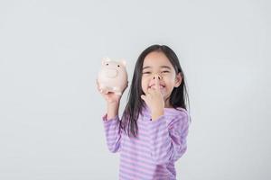 petite fille asiatique économisant de l'argent dans une tirelire, apprenant à économiser, enfant économisant de l'argent pour l'éducation future. concept d'argent, de finances, d'assurance et de personnes photo