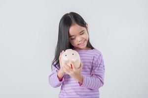 petite fille asiatique économisant de l'argent dans une tirelire, apprenant à économiser, enfant économisant de l'argent pour l'éducation future. concept d'argent, de finances, d'assurance et de personnes photo