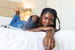 portrait de magnifique et sensuel africain Jeune femme mensonge sur lit. magnifique femme mensonge dans lit photo