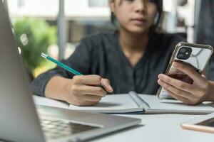 femme mains avec stylo l'écriture sur carnet dans le office.learning, éducation et travail.écrit buts, des plans, faire à faire et souhait liste sur bureau. photo