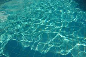 bleu déchiré l'eau dans nager bassin. texture de l'eau surface. photo