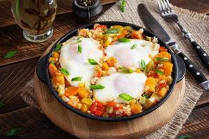 shakshouka dans friture poêle. frit des œufs avec légumes, tomate, poivre, citrouille et oignon photo