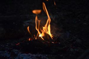 brûlant bois journaux dans le nuit. flou lumière. brillant rouge Feu. la nature photo. photo