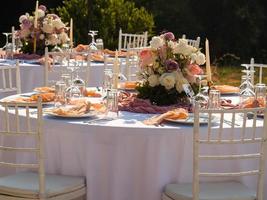 magnifique Extérieur mariage décoration dans ville. bougies et séché fleurs et accessoires avec bouquets et des lunettes sur table avec lin nappe de table sur nouveau marié table sur vert pelouse photo