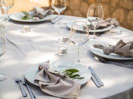 mariage banquet concept. chaises et rond table pour invités, servi avec coutelier et, fleurs et vaisselle et couvert avec une nappe de table photo