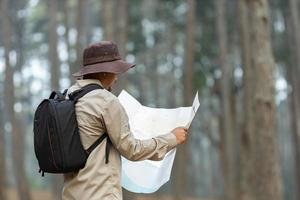 naturaliste à la recherche à le carte pour direction tandis que explorant faune dans le pin forêt pour arpentage et découvrir le rare biologique la diversité et écologiste sur le champ étude concept photo