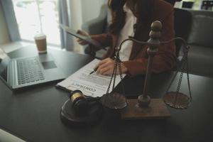 concept de justice et de droit. un conseiller juridique présente au client un contrat signé avec un marteau et un droit juridique ou juridique ayant une réunion d'équipe au cabinet d'avocats en arrière-plan photo