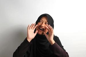 de bonne humeur Jeune asiatique fille dans hijab en criant bruyamment récit à propos bien nouvelles isolé sur blanc Contexte. photo