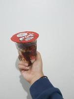 bekasi, Indonésie dans Mars 2023. isolé blanc photo de une main en portant une tasse de mélange la glace crème surmonté avec oréos et Chocolat.