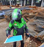 Djakarta, Indonésie dans mai 2022. une gojek chauffeur est cueillette en haut une paquet de les documents à être expédié à le destinataire. photo