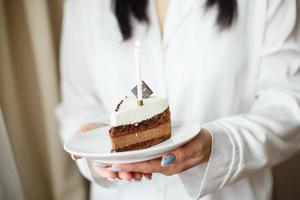 femme tenant un morceau de gâteau avec une bougie photo