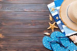 chapeau de paille, tongs bleues, serviette et étoile de mer sur un fond en bois foncé. vue de dessus concept de vacances d'été avec espace de copie photo