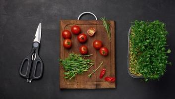 rouge tomate et germé pois des graines sur une noir arrière-plan, microgreens pour salade, détox. Haut vue photo