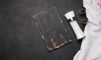 vide noir en bois conseil, sel dans une verre bouteille sur une noir tableau, Haut vue photo