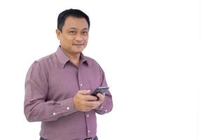asiatique affaires adulte homme est en portant téléphone intelligent mobile téléphone dans le sien main et à la recherche à caméra isolé sur blanc Contexte. photo