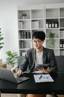 Jeune affaires homme exécutif directeur à la recherche à portable en train de regarder en ligne séminaire en ligne formation ou ayant virtuel réunion vidéo conférence Faire marché recherche travail dans bureau. photo