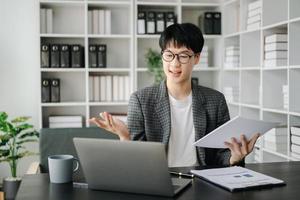 Jeune affaires homme exécutif directeur à la recherche à portable en train de regarder en ligne séminaire en ligne formation ou ayant virtuel réunion vidéo conférence Faire marché recherche travail dans bureau. photo